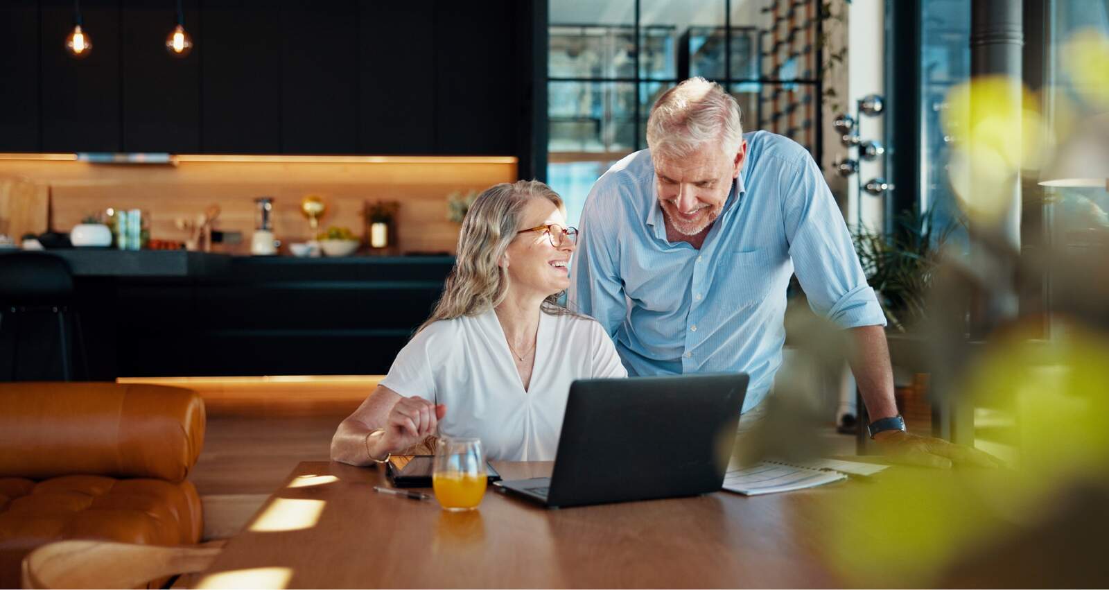 A couple smiling at a laptop together at home